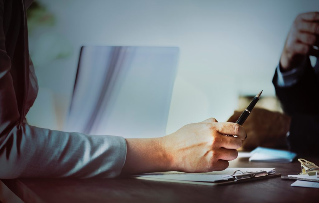 woman holding a pen and having a discussion with a colleague in a suit