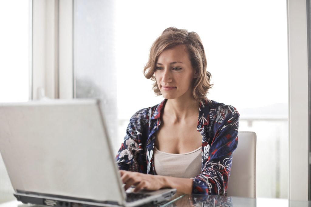 woman with bright hair typing on her laptop