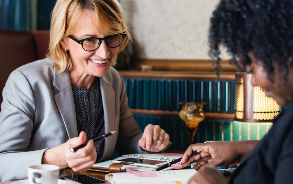 older professor smilingly explaining details to her student