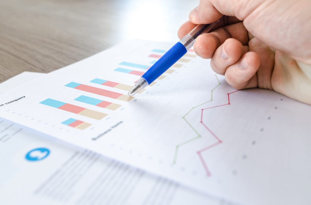 close-up shot of a man using a pan to point at analytics charts