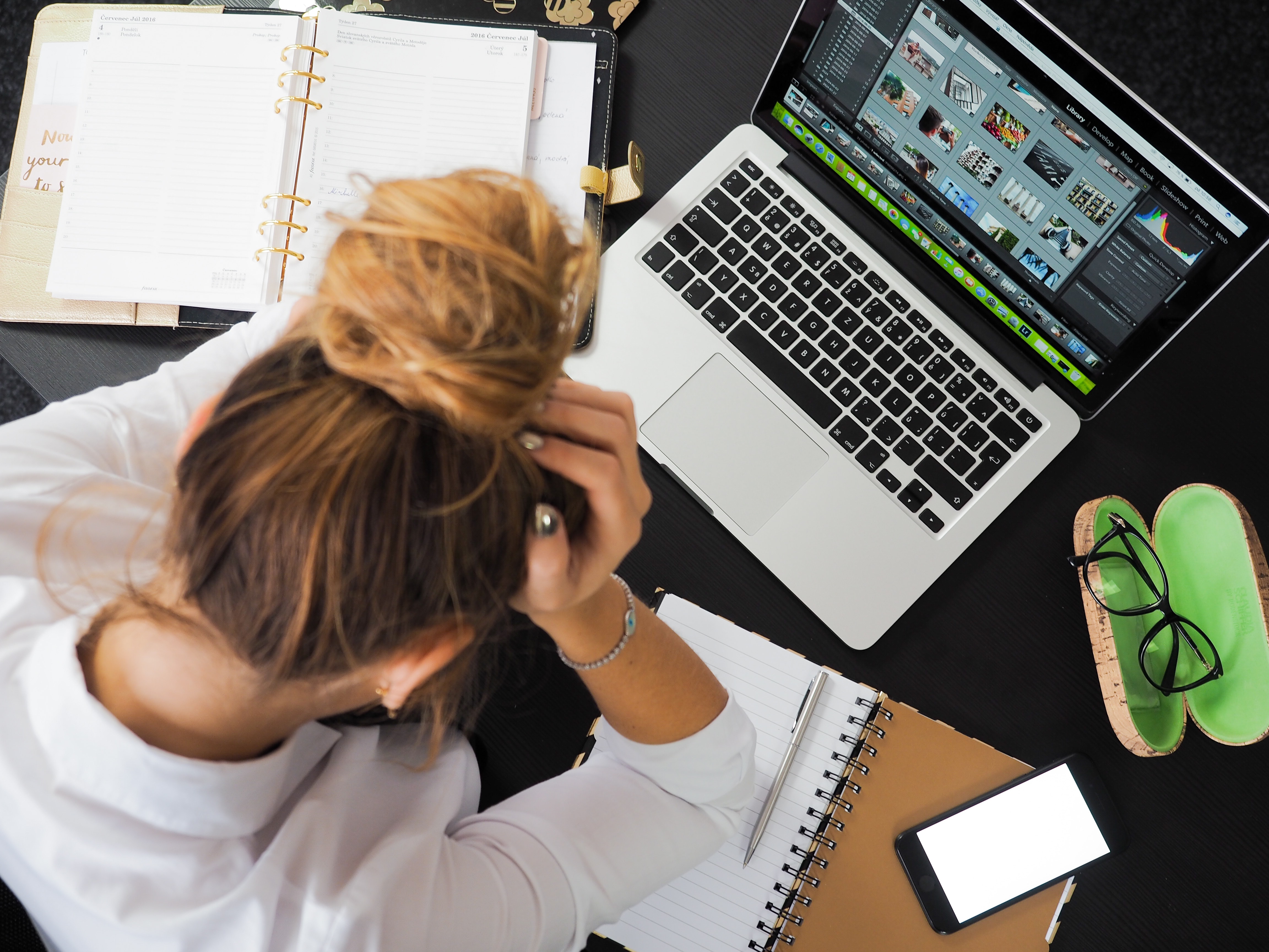 top view of a stressed out woman holding her head in front of laptop