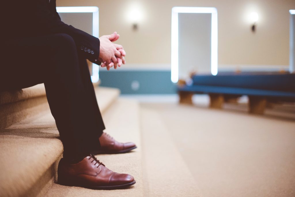 man in black suit and brown shoes waiting on the stairs