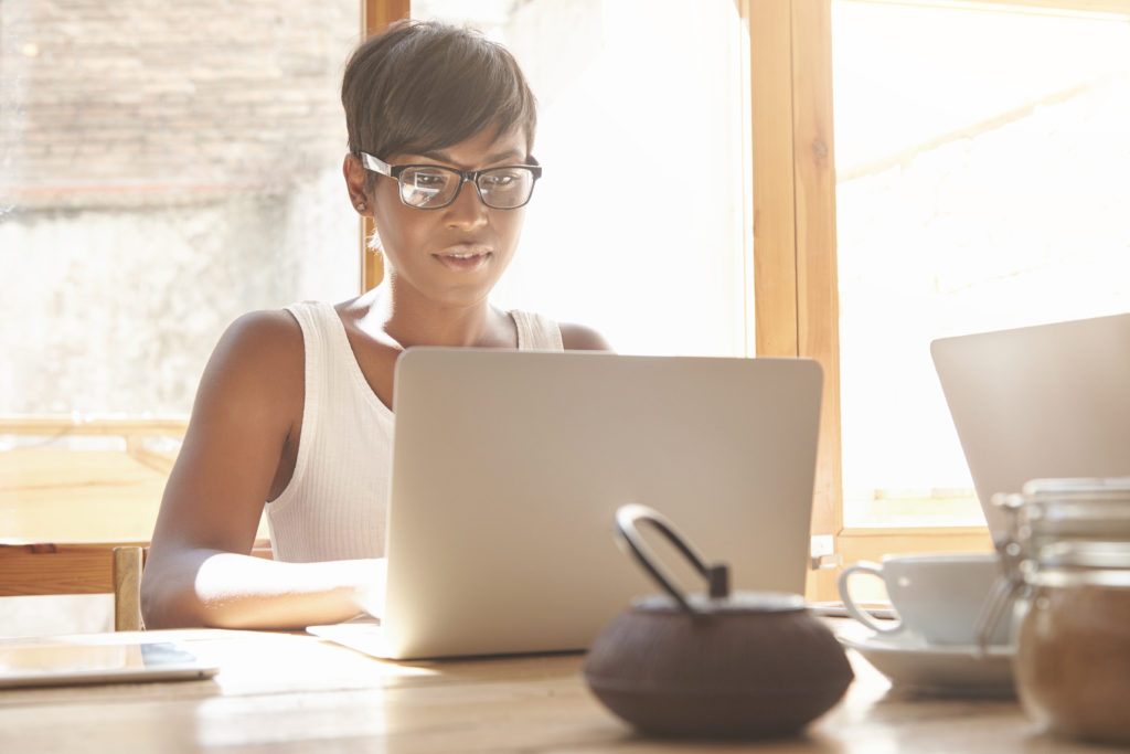 african american woman with short hair studying on her laptop