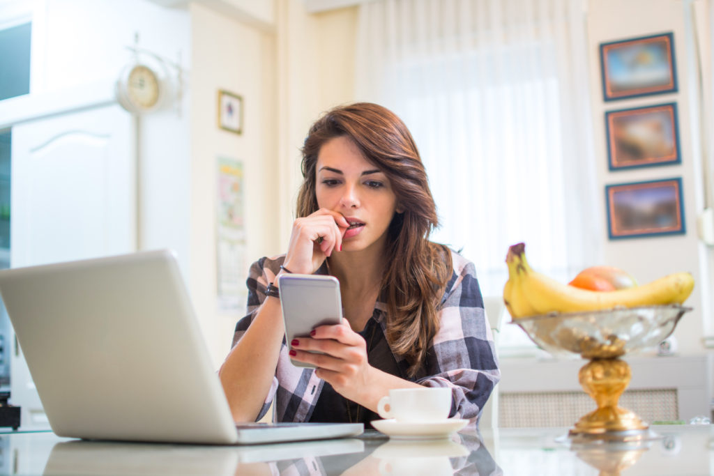 worried woman looking at her phone in a home kitchen