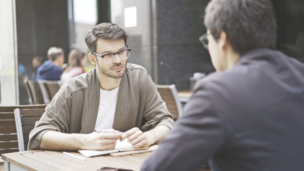 student and professor having a discussion in the college cafeteria