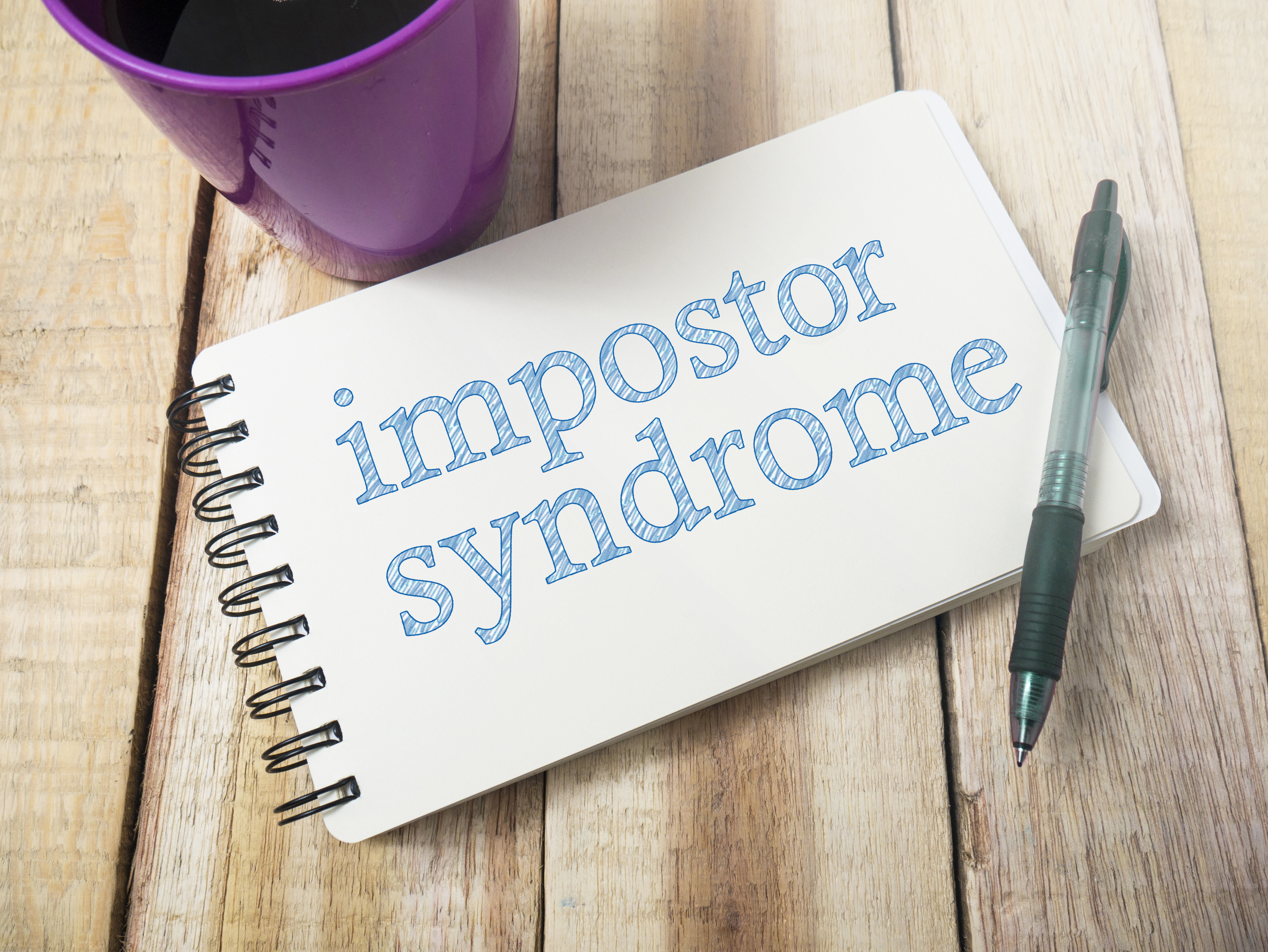 impostor syndrome written in blue ink on a notepad