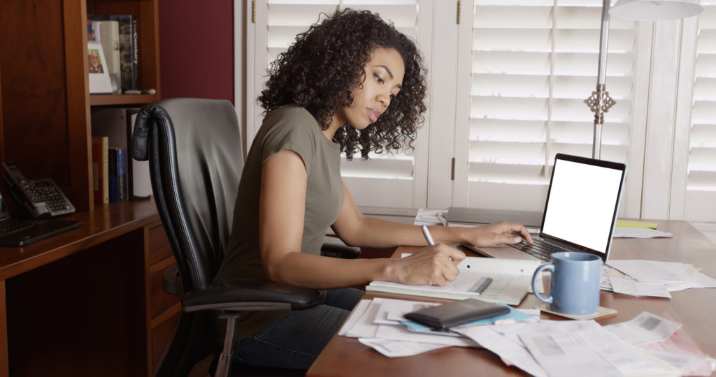 woman with curly hair taking notes in her home office