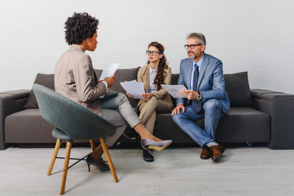 woman being interviewed by two people sitting on a couch