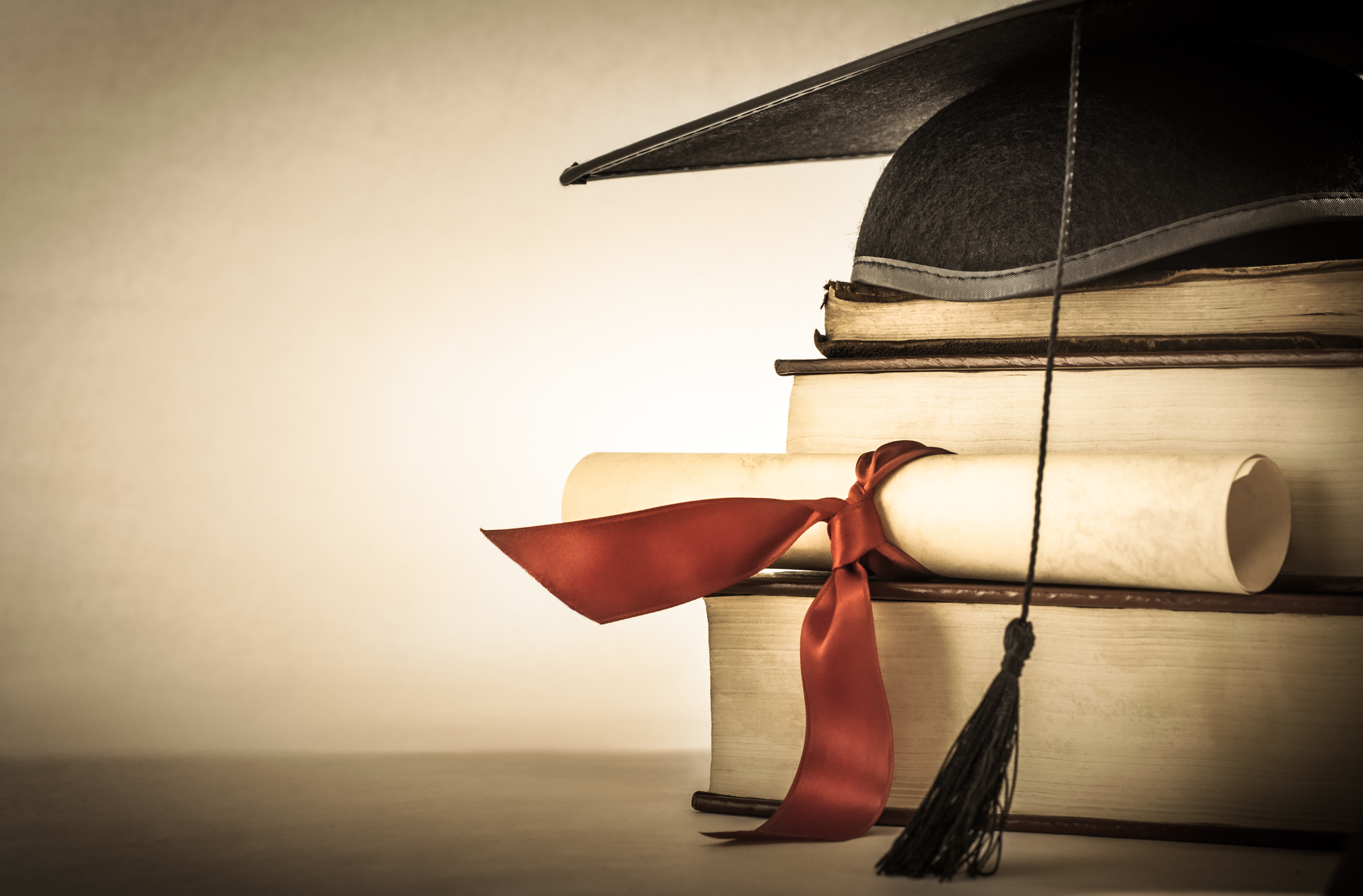 close-up shot of a diploma and a graduation hat on top of books