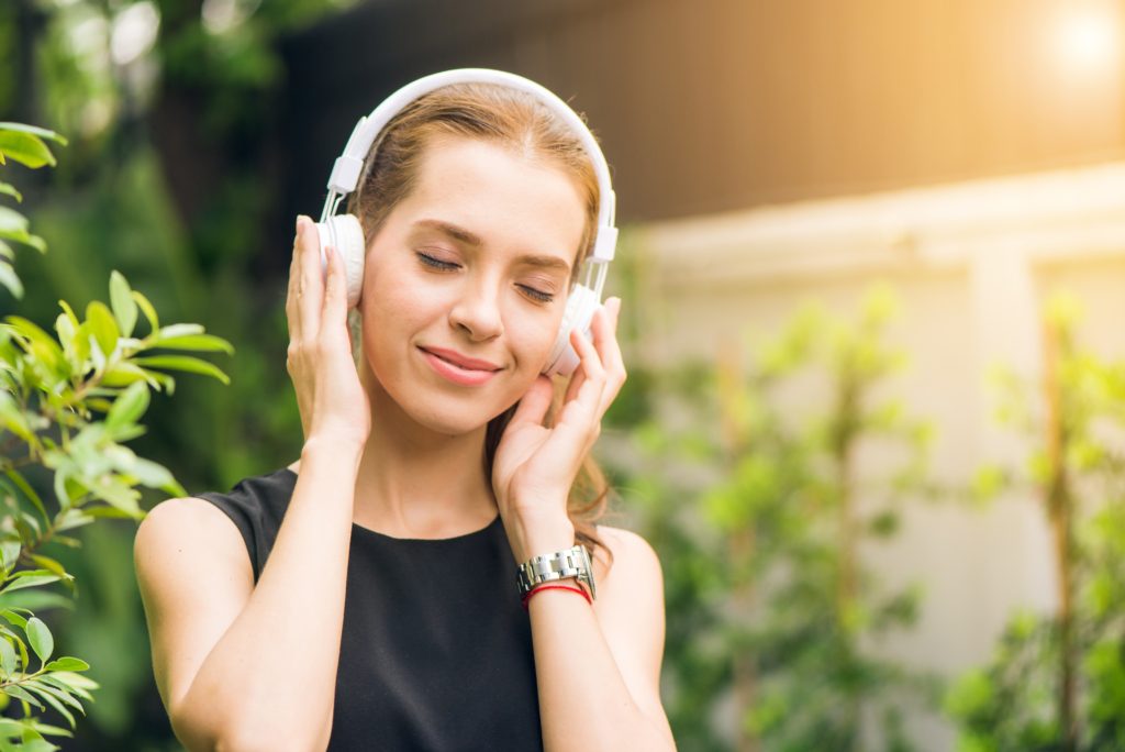 happy woman listening to headphones outdoors