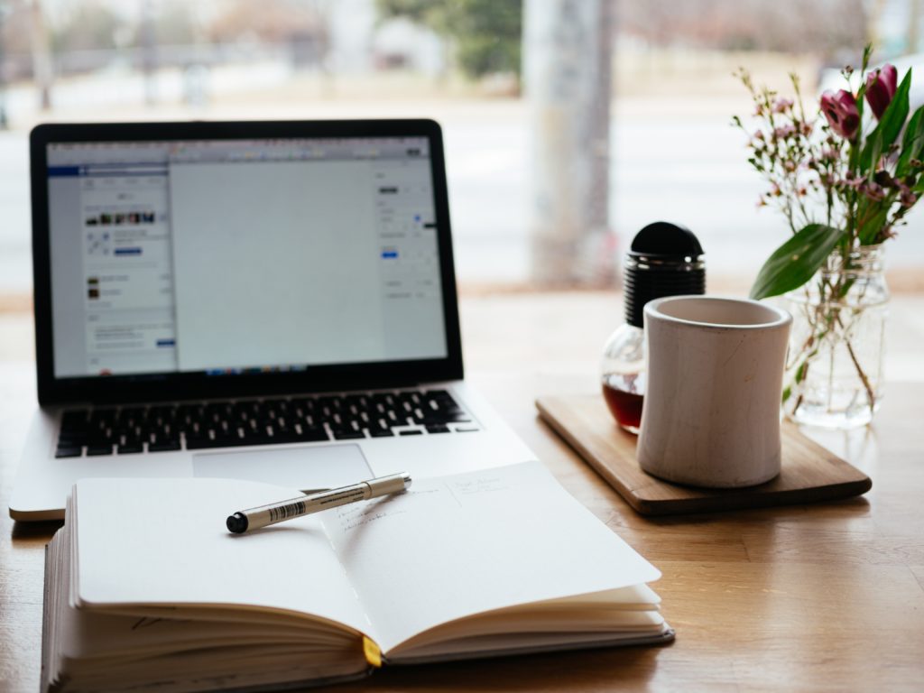 close-up shot of an open notebook and a laptop