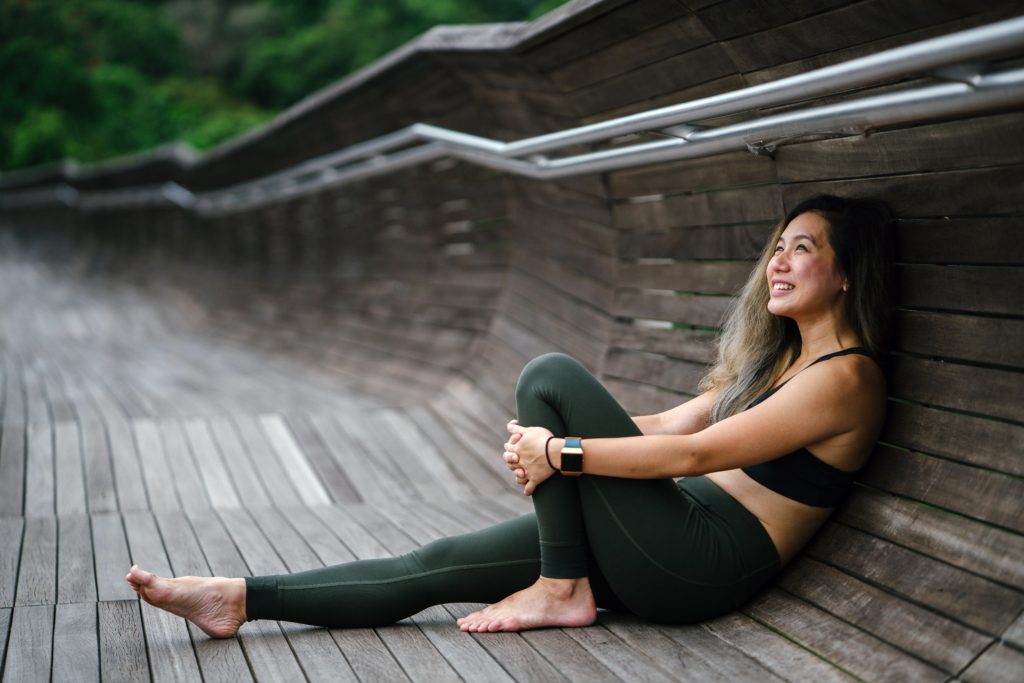 woman in sportswear sitting in an outdoor park and smiling