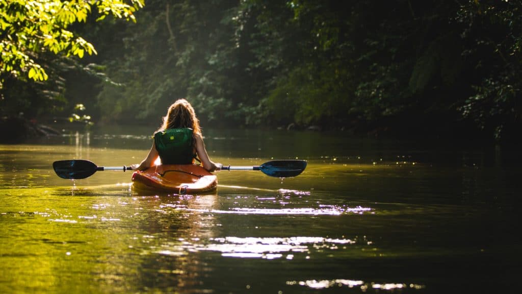 woman kayaking through a lush green landscape