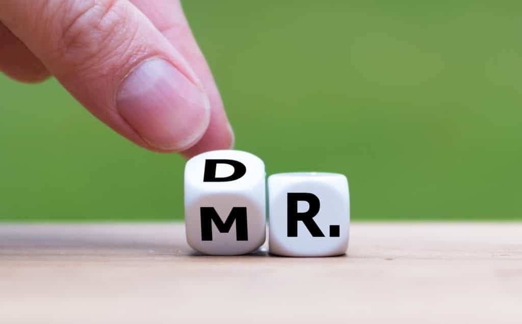 hand flipping dice that spell out both Dr. and Mr.