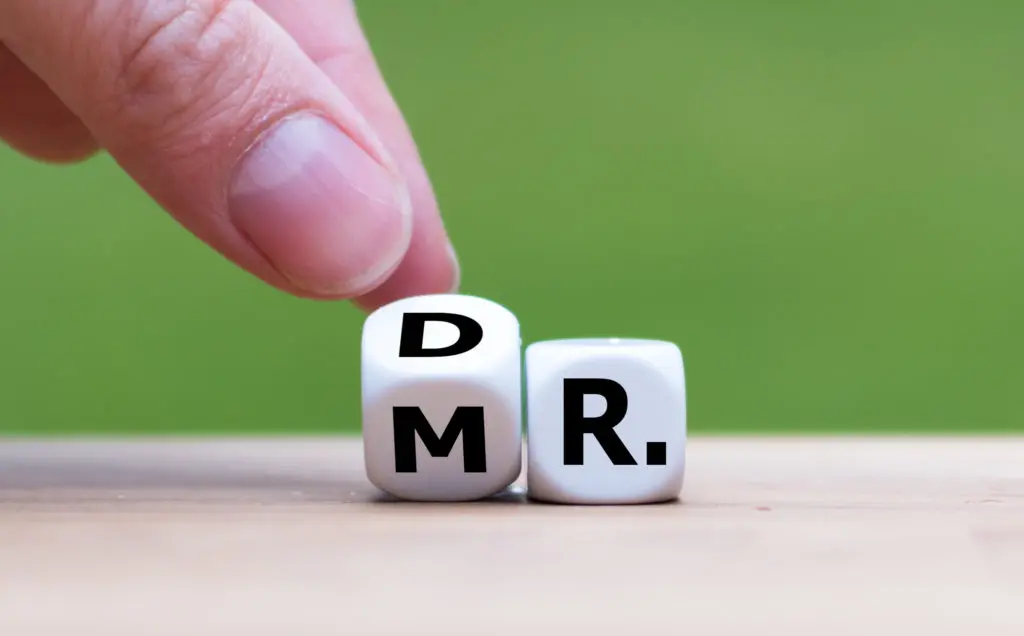 hand flipping dice that spell out both Dr. and Mr.