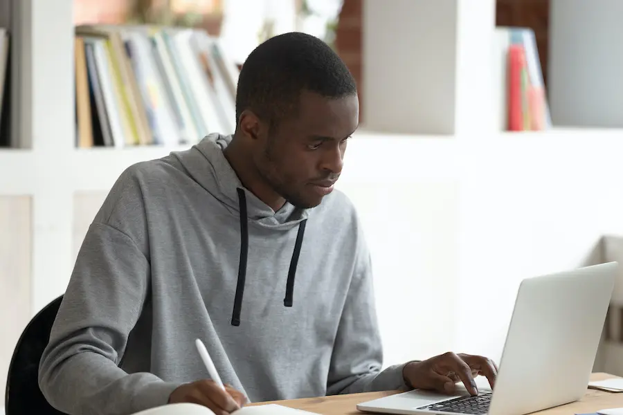 focused student studying on his laptop in a library