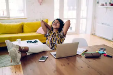 woman smiling and relaxing at home with her feet up on the table