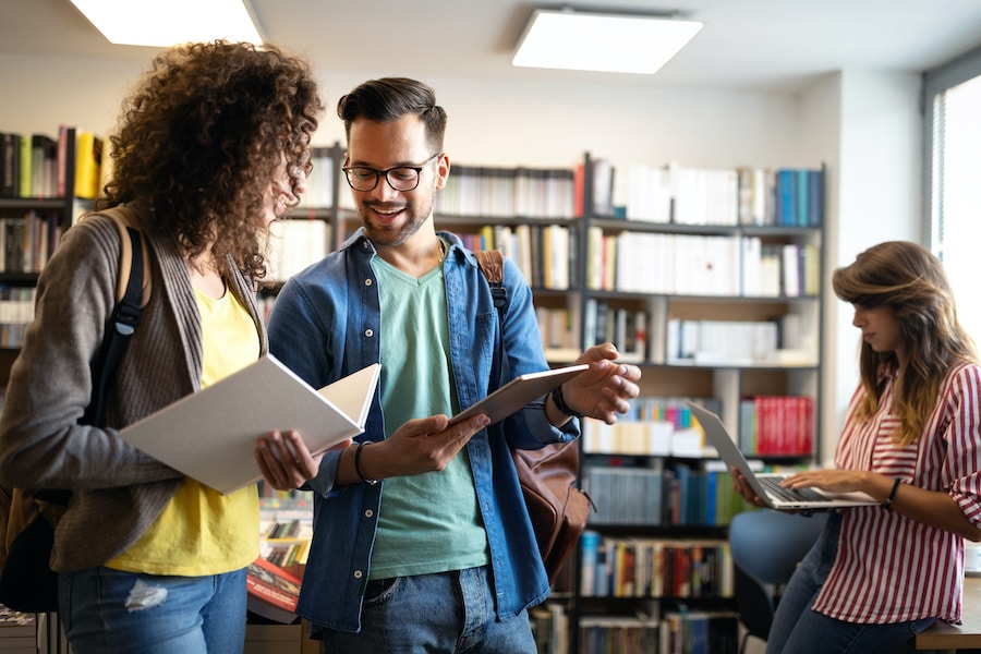 two colleagues comparing notes inside a library