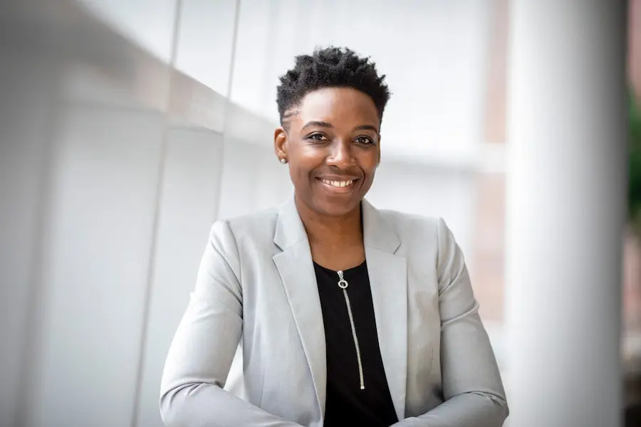 african american woman with short hair and a white jacket smiling towards the camera