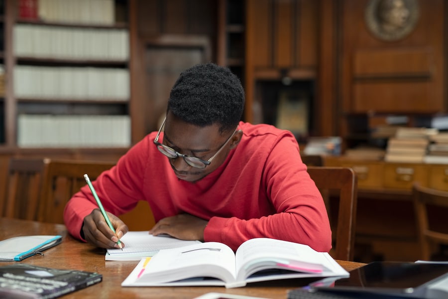 african american man in red sweater doing research inside a library