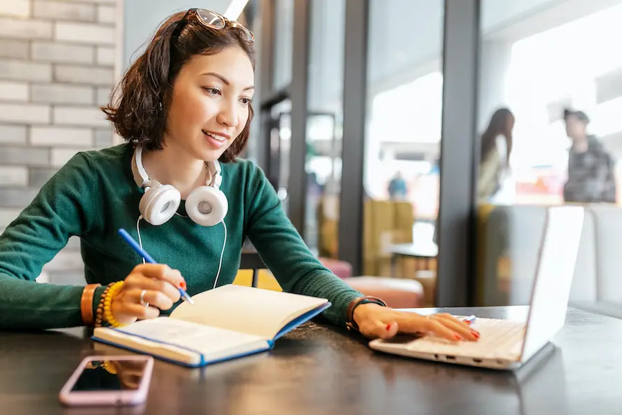 woman smiling and studying in a coffee shop