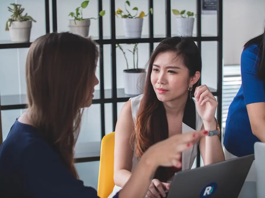 two women discussing details in front of a laptop