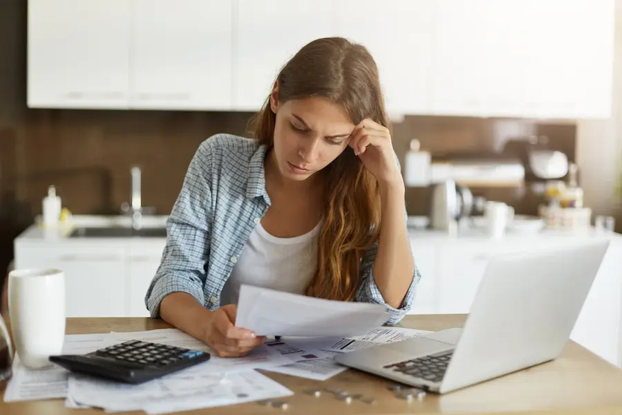 woman stressing about calculating her budget in her home kitchen