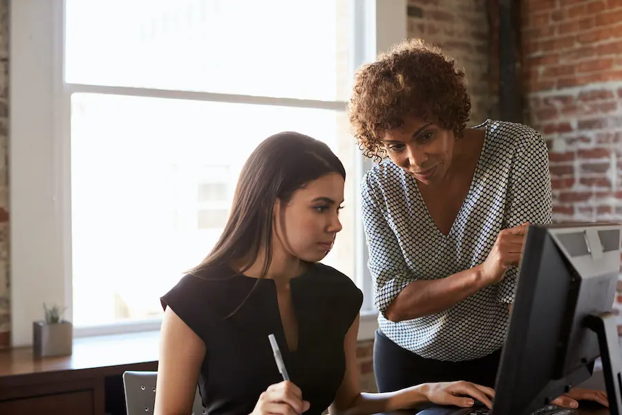 professor explaining something to her student on the computer