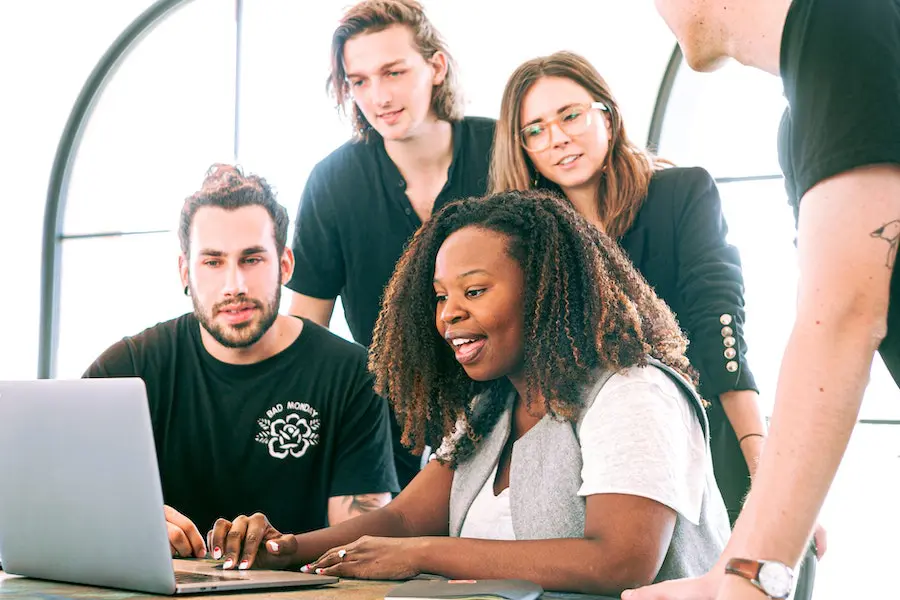 multicultural group of people all collaborating together on a laptop