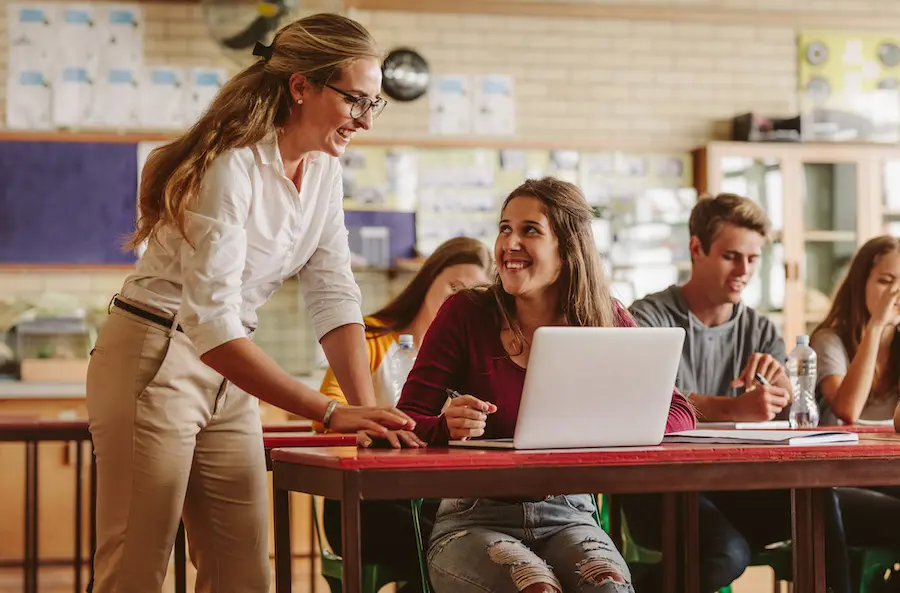 professor showing something to her students on a laptop