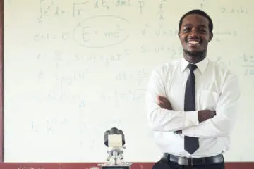 man in a suit and tie confidently smiling towards the camera against a white wall