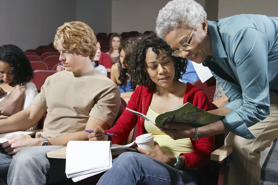 two women comparing notes inside a college auditorium