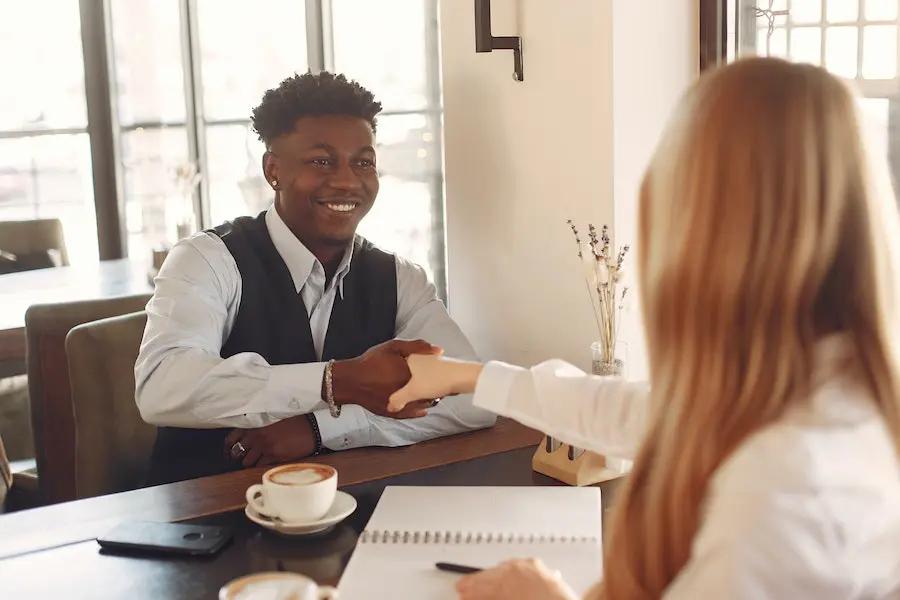 man and woman shaking hands over a cup of coffee