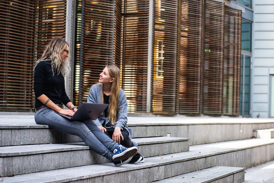 two blonde women sitting on the stairs and chatting