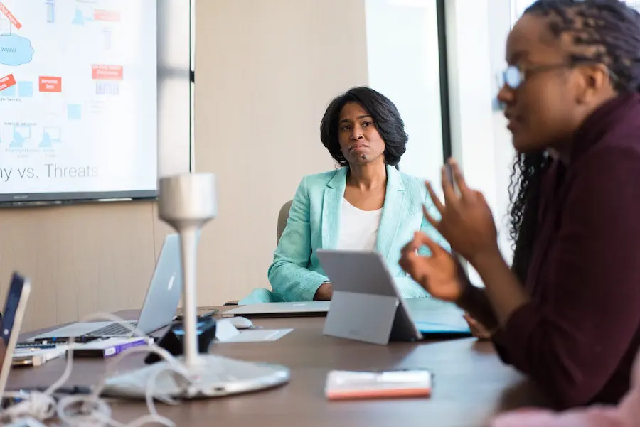 woman in a bright suit jacket looking at her student giving a presentation