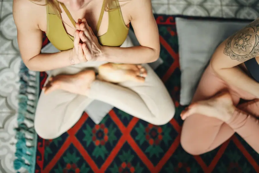 top view of two women practicing yoga on a colorful rug