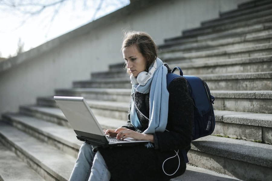 woman sitting on the campus stairs and working on her laptop