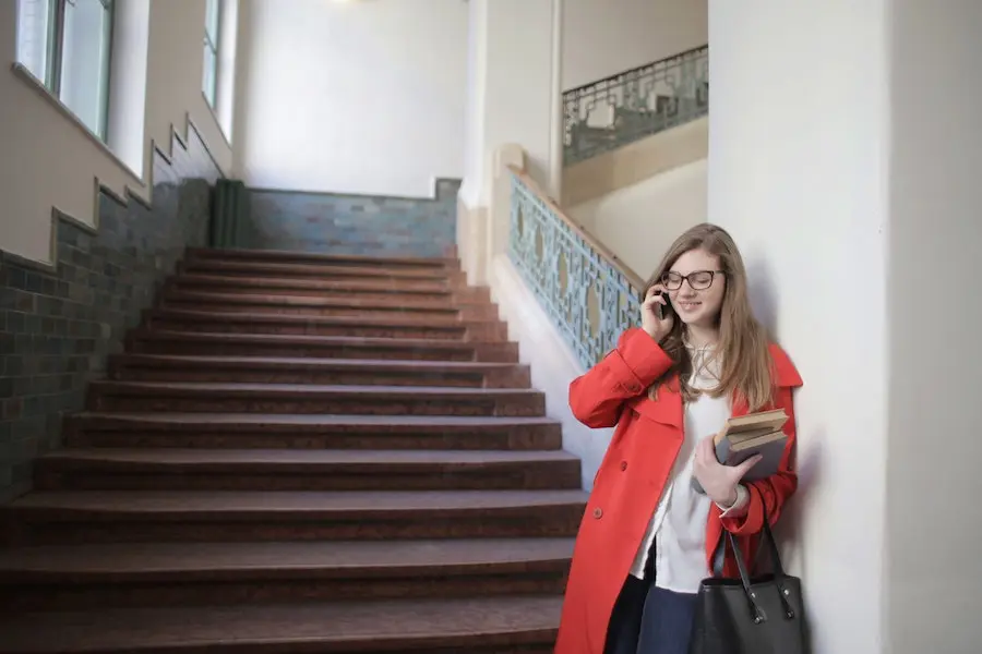 woman smiling and talking on her phone next to the stairs at a university