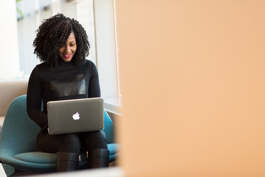 woman in all black clothes typing on her laptop