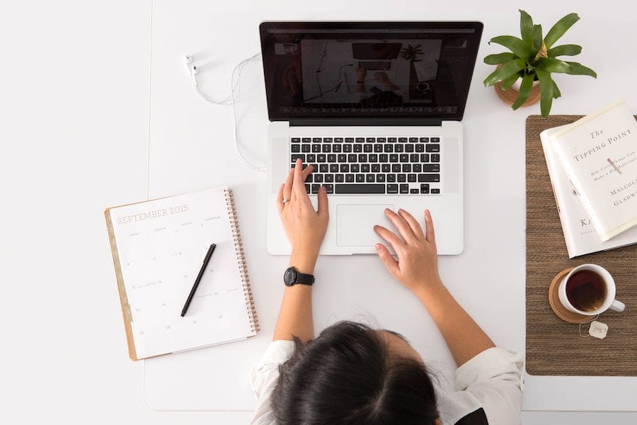 top view of a woman working on her laptop with a cup of tea next to her