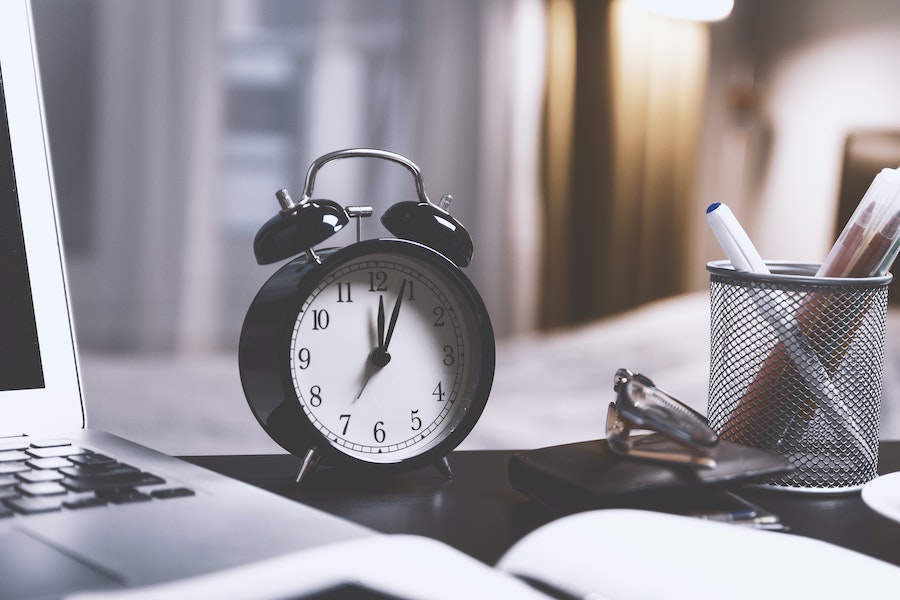 close-up shot of an alarm clock next to a laptop