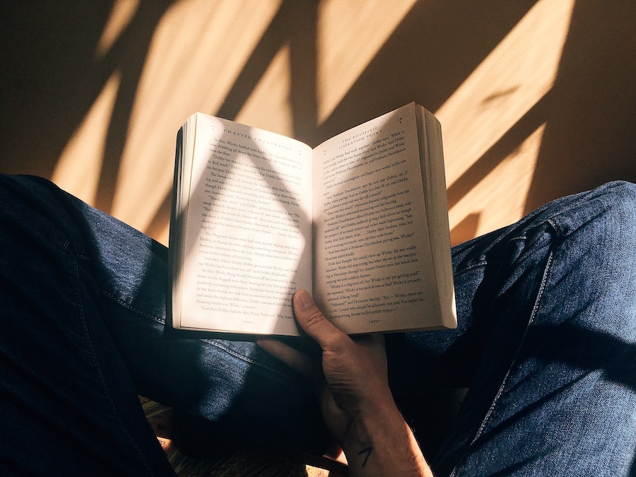 first person view of a man reading a book in the sunlighyt