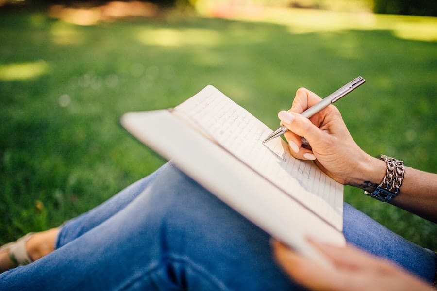 close up shot of a woman wriing in a notebook at the park