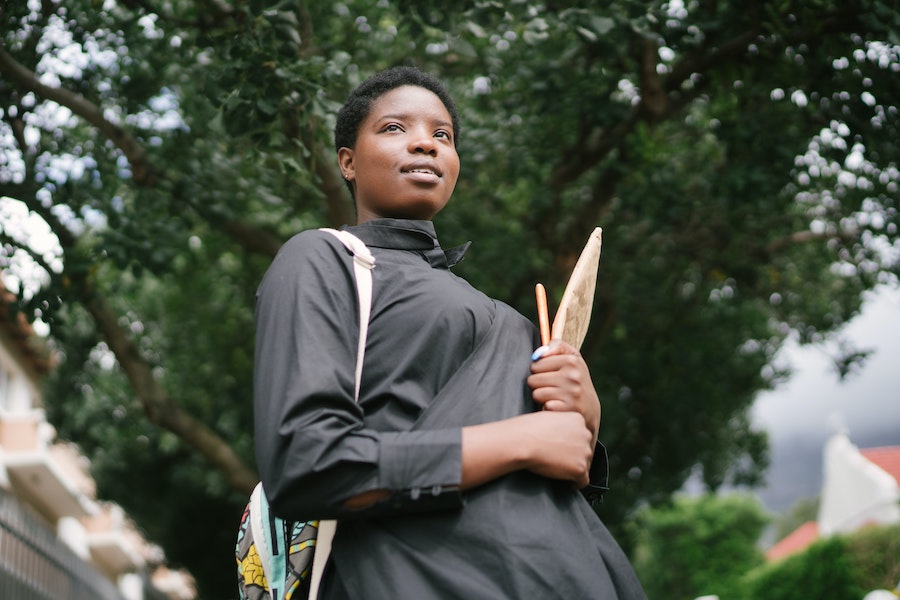 african american woman holding notebooks in university campus