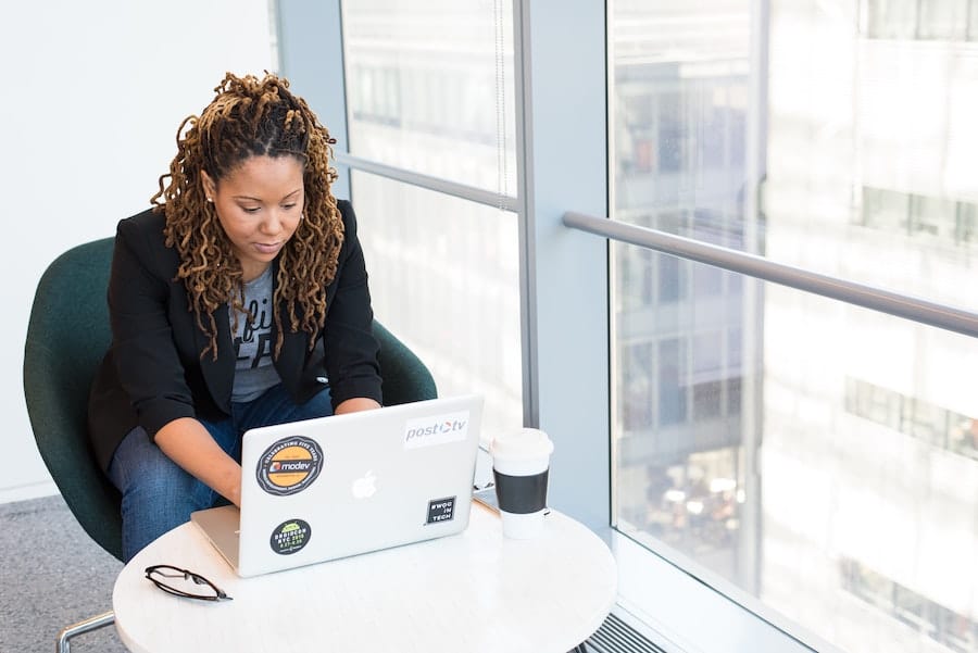 woman typing on her laptop in a bright office space next to the window