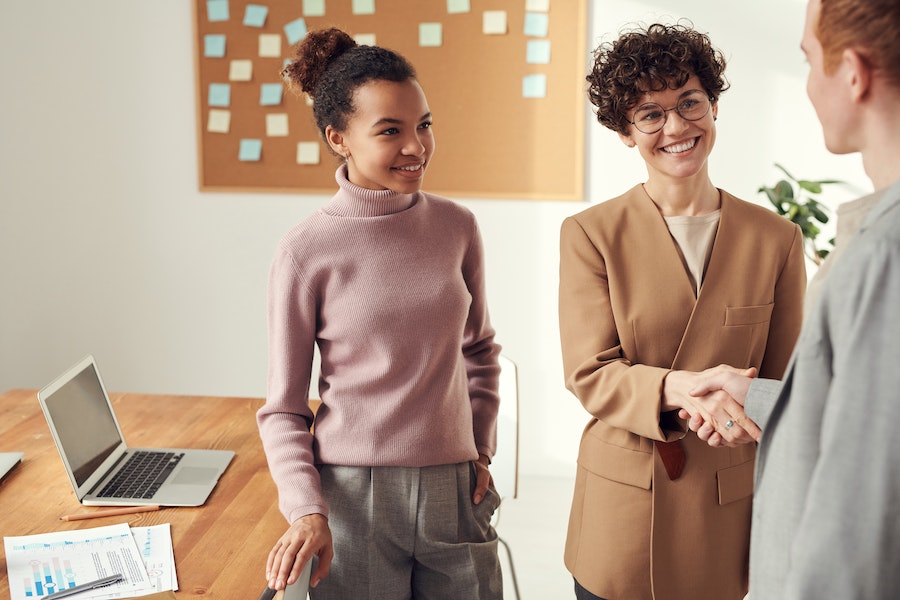 woman with curly hair shaking hands with a business associate