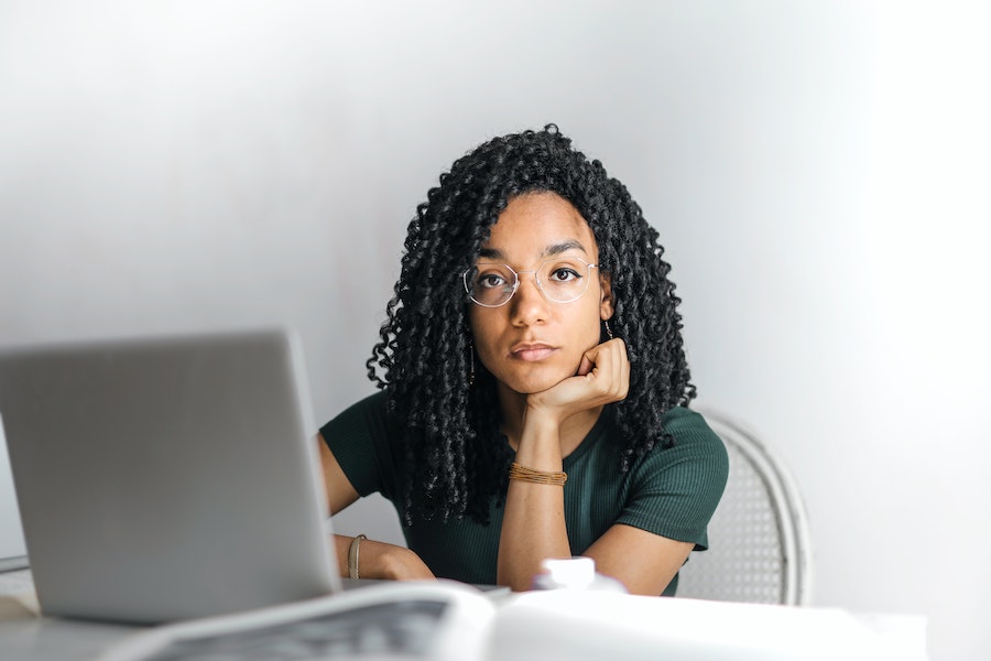 serios woman with curly hair looking at the camera while working on her laptop