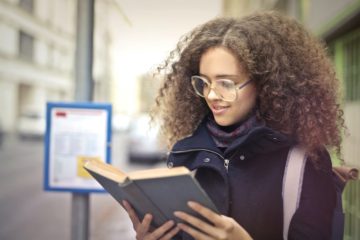 woman with curly hair reading a book outside