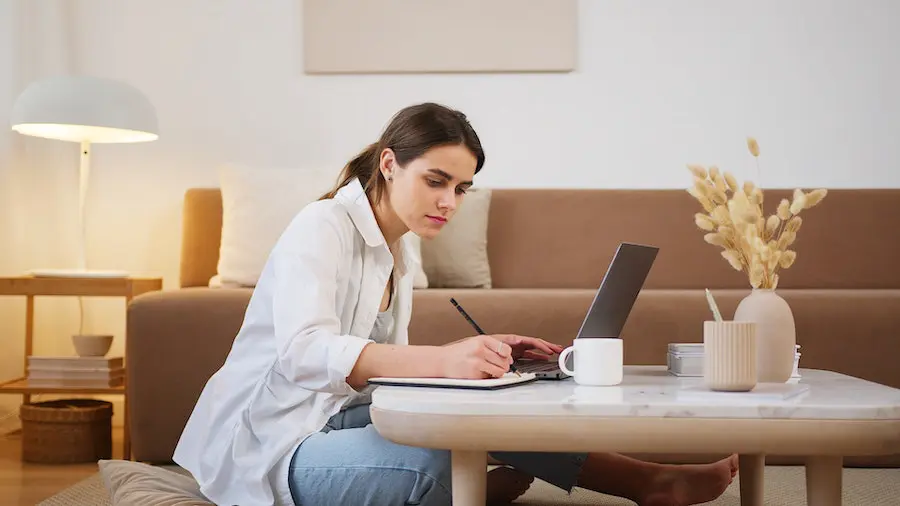 woman sitting on the floor at home and studying on her laptop