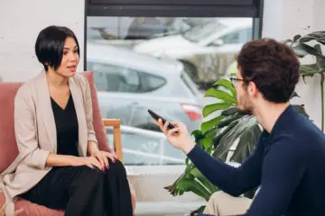 reporter recording a conversation with a woman with short hair